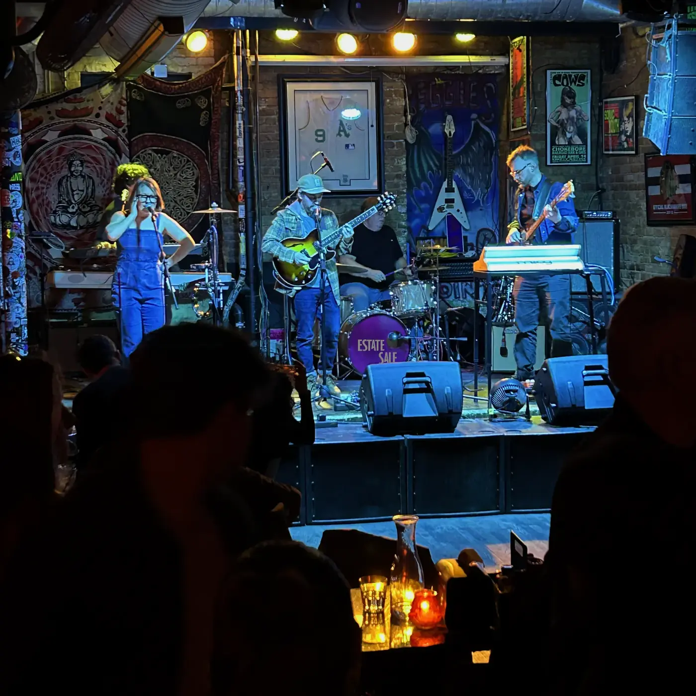The band on a blue-lit stage seen from the crowd