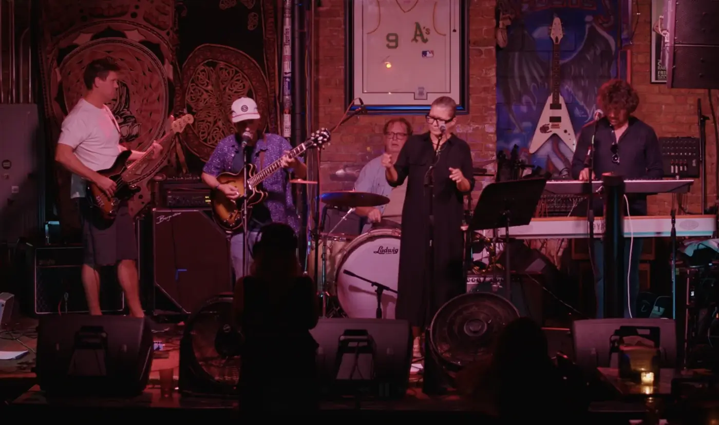 The full band performing under red stage lights
